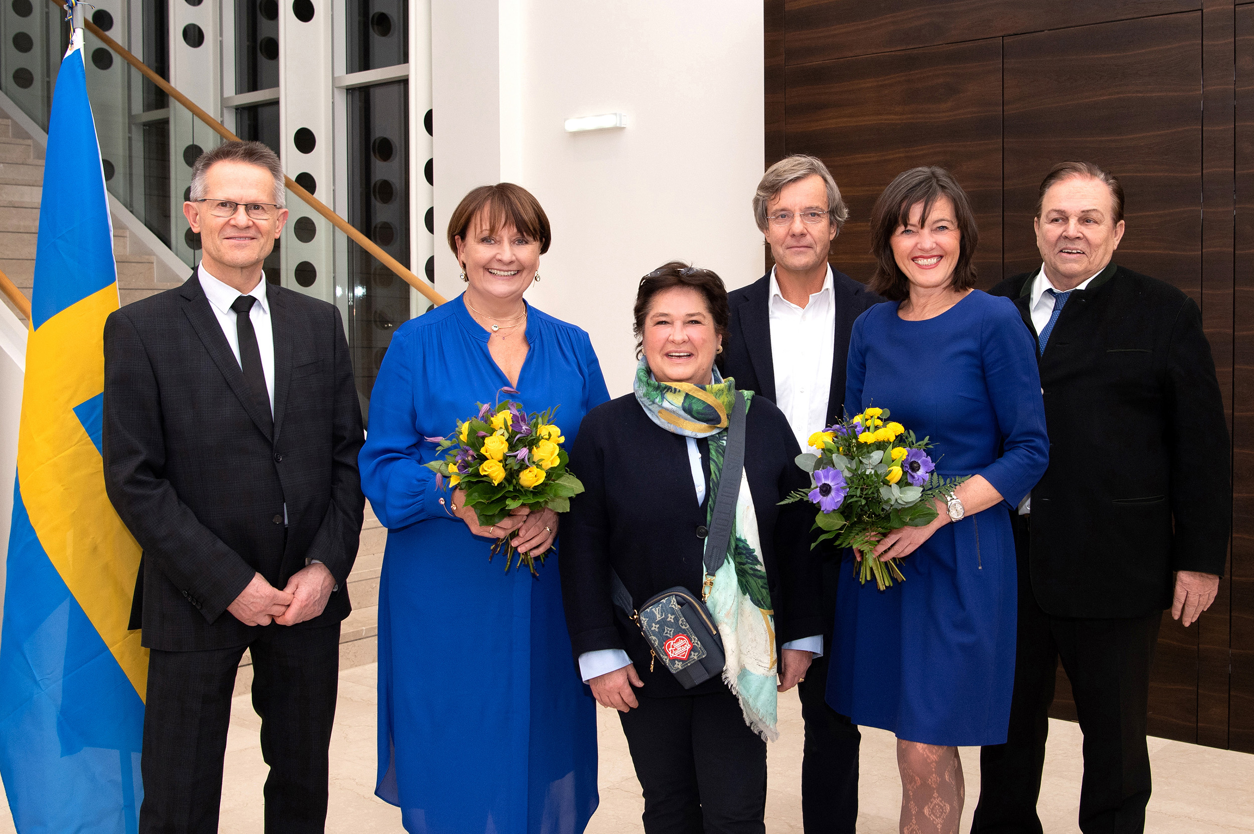 Sechs Personen darunter Frau Herta Stockbauer stehen in der BKS Bank Zentrale vor dem Stiegenaufgang. Links im Bild ist die schwedische Flagge zu sehen.