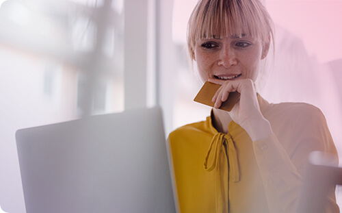 Frau vor Laptop mit Karte in der Hand