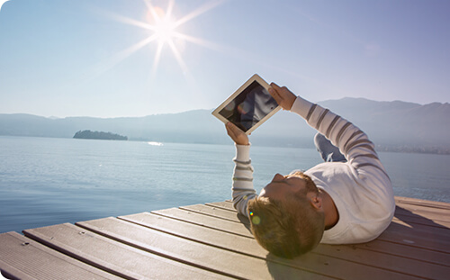 Mann auf Bootssteg liegend mit Tablet.