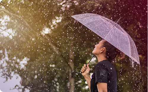 Frau steht mit Regenschirm im Regen